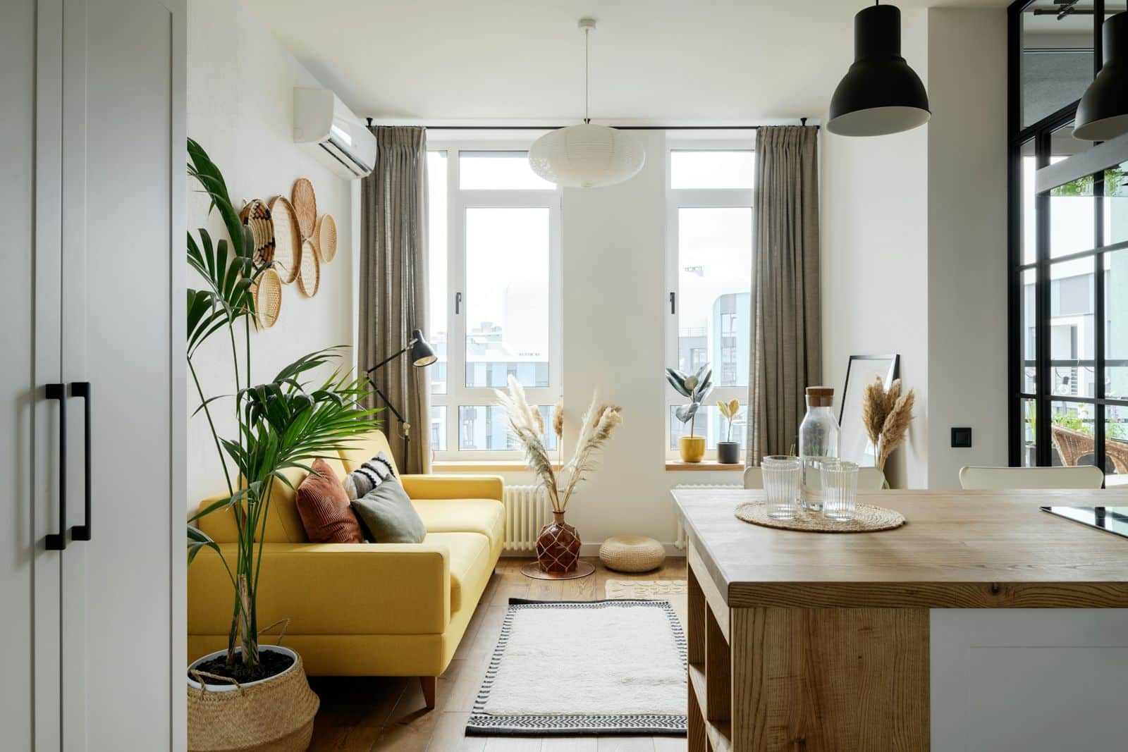 A furnished rental flat with a sofa, rug and curtains, and a kitchen island.